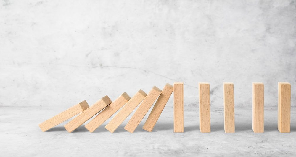 Hand stopping the Domino effect stopped by unique, Business Ideas